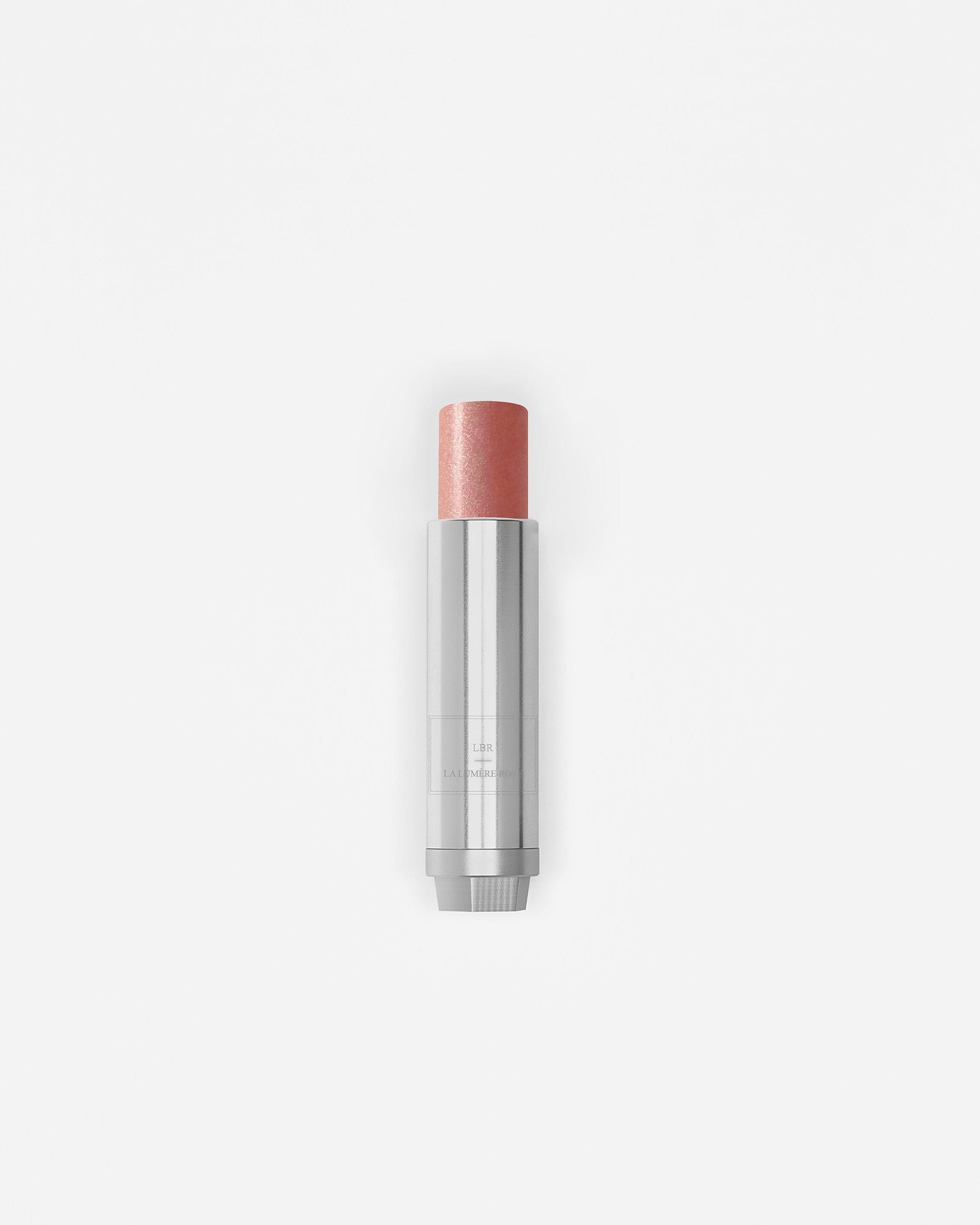 Stick enlumineur La Bouche Rouge Paris avec teinte rose, appliqué sur la peau pour un éclat naturel et lumineux.
