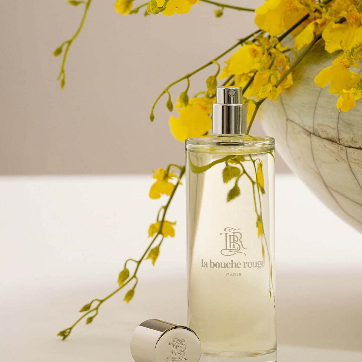 Flacon de parfum Capri Lumière Jaune de La Bouche Rouge Paris avec design élégant, visible dans une image lumineuse et sophistiquée.