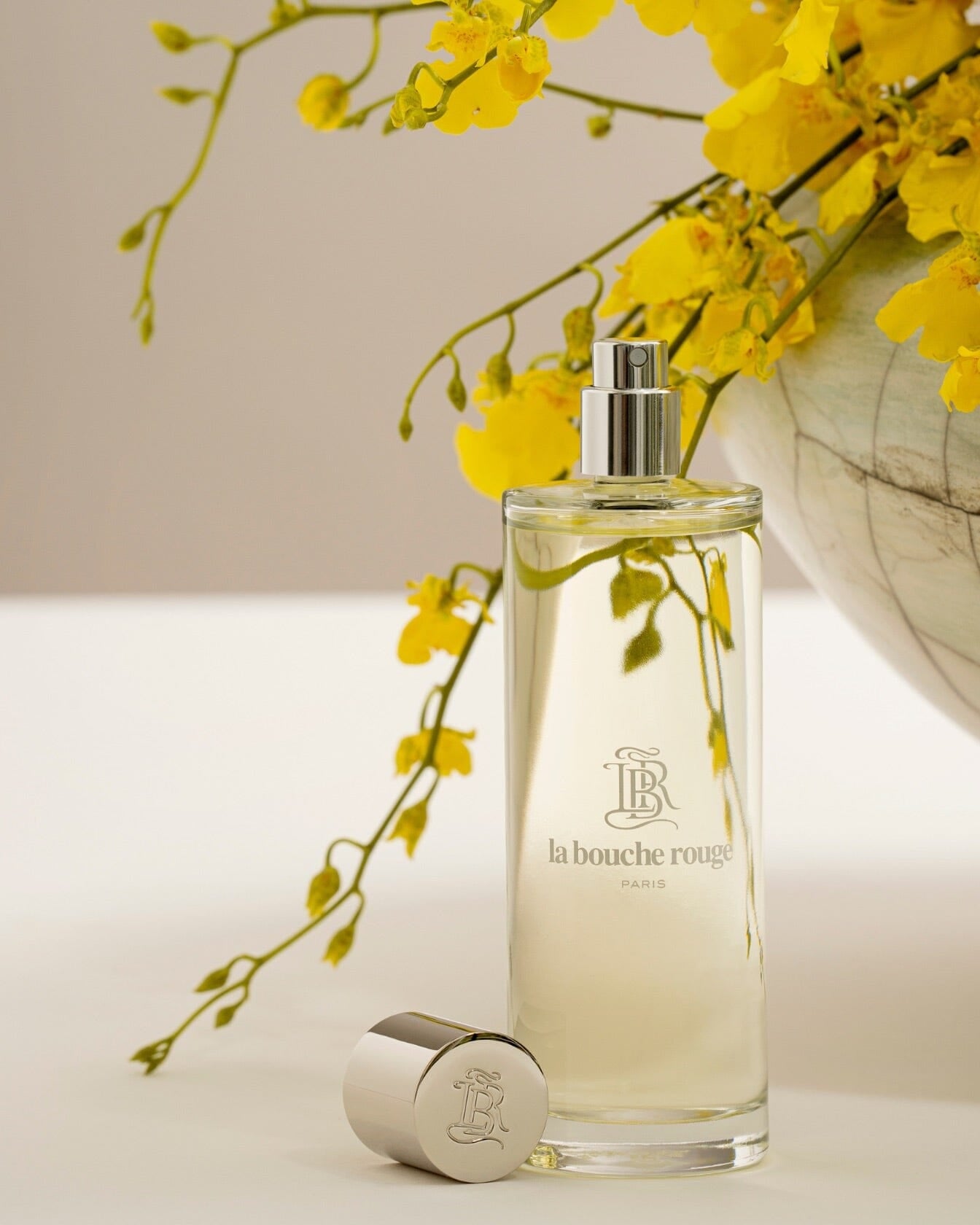 Flacon de parfum Capri Lumière Jaune de La Bouche Rouge Paris avec design élégant, visible dans une image lumineuse et sophistiquée.