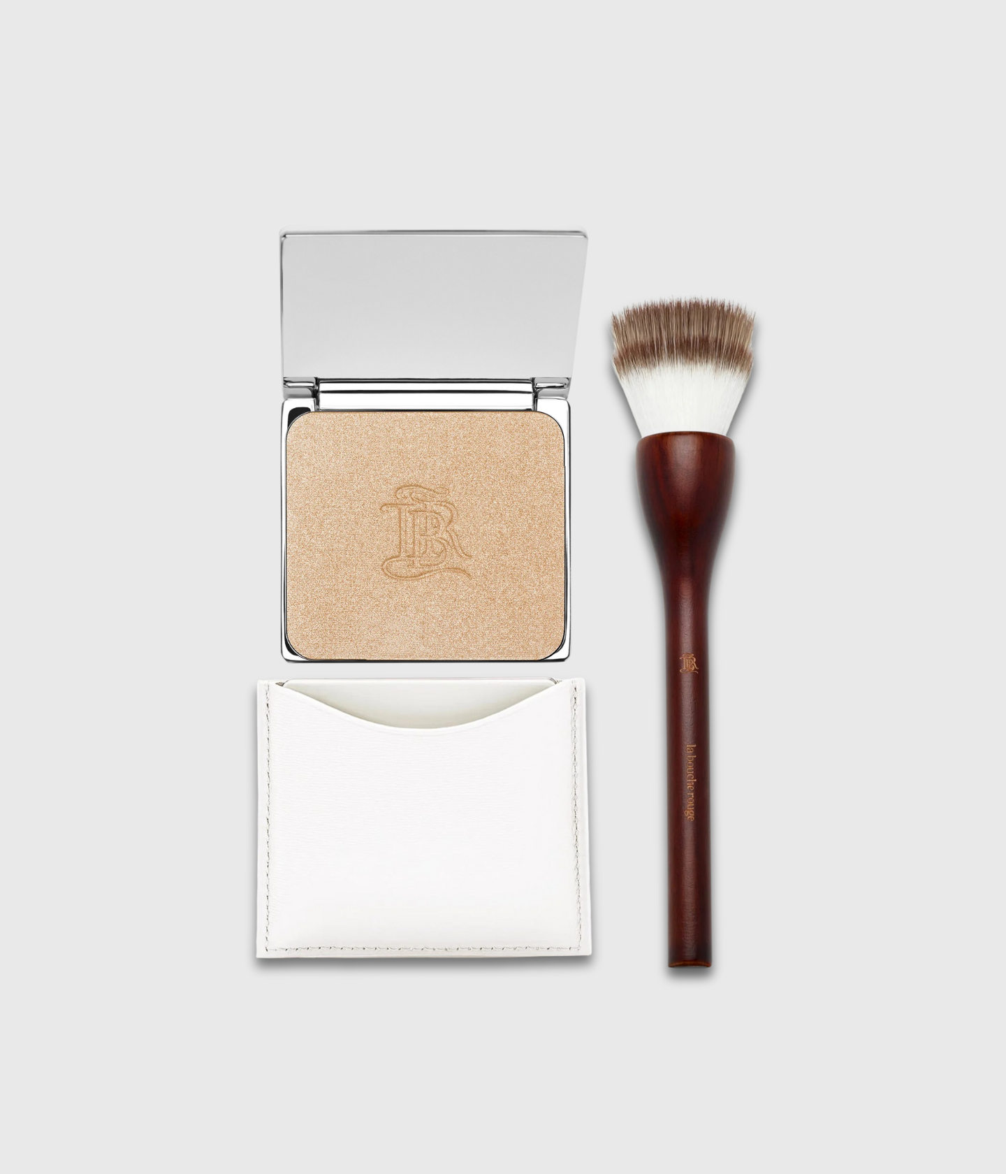 Le Rituel Lumière La Bouche Rouge — poudrier compact blanc rechargeable en cuir fin contenant la poudre enlumineur La Lumière, accompagné du pinceau poudre en bois de hêtre et fibres véganes. 
Le Rituel Lumière by La Bouche Rouge — white refillable leather compact with La Lumière highlighter powder, accompanied by the beechwood powder brush with vegan fibers.